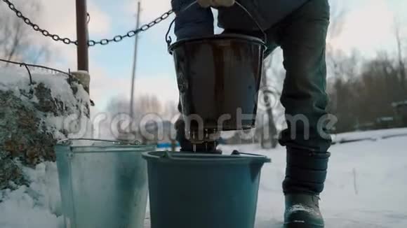 村里一个冬天的老人从井里打水然后把水倒进水桶里视频的预览图
