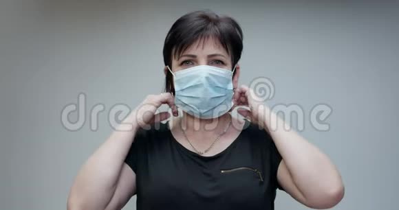 女人脱下医疗面具孤立在灰色背景上深呼吸微笑着看着相机保健视频的预览图