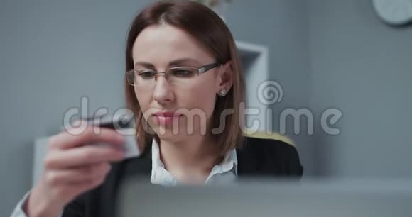 女人在网上购买在线支付服务关闭女性手拿信用卡并使用笔记本电脑进行视频的预览图