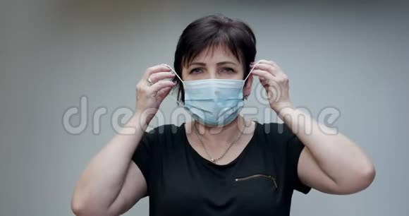 高级妇女参加医疗面具深呼吸看着灰色背景上的相机保健和医疗视频的预览图