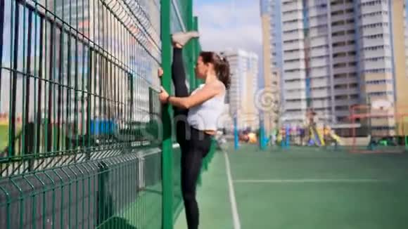 运动女孩在围栏附近的运动场上训练后做一根垂直的麻绳视频的预览图