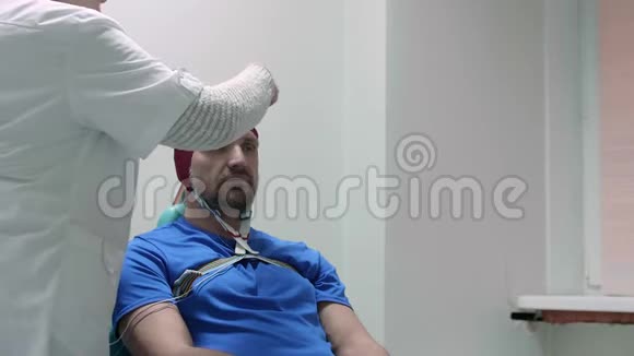 医生将传感器连接到前来检查的病人头部的脑电图帽上视频的预览图