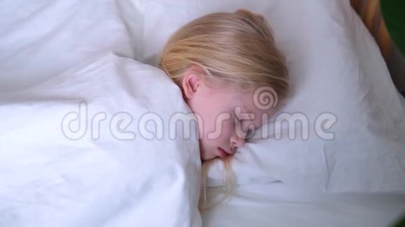 睡着的金发小女孩一大早就躺在大床上铺着白色床上用品上景儿童梦视频的预览图