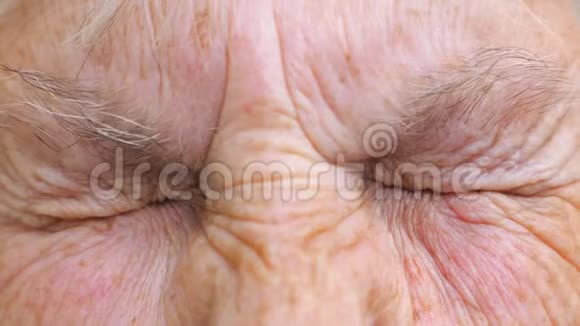 年长的女人看着镜头强烈地扭曲了她的眼睛闭上布满皱纹的女性脸睁大眼睛视频的预览图