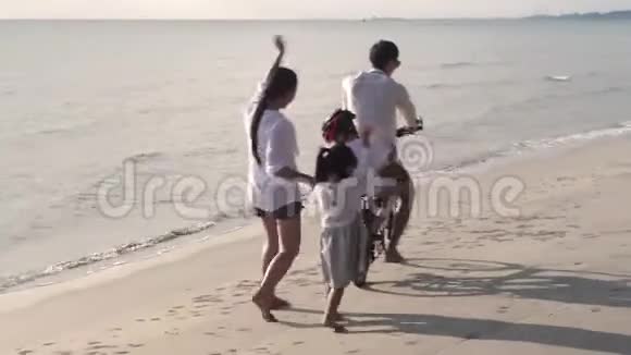快乐的亚洲家庭父子俩骑自行车母女俩一起在海滩上散步度假视频的预览图