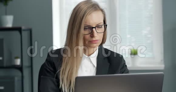 在笔记本电脑上工作的戴眼镜的成熟女人视频的预览图