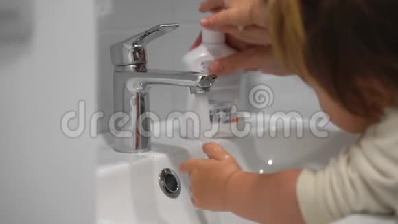年轻母亲带着孩子在家用抗菌肥皂洗手视频的预览图