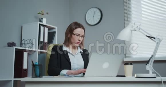 在她自己的办公室里商务妇女坐在桌子旁打电话成功的概念视频的预览图