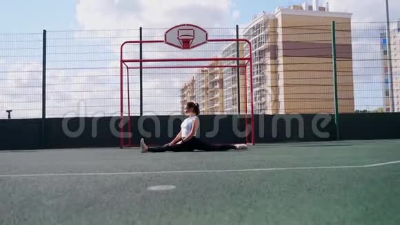 伸展体操女子在运动场地做劈叉缠绕视频的预览图