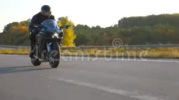 摩托车手在秋天的乡村公路上骑摩托车戴着头盔的年轻人骑着现代摩托车视频的预览图