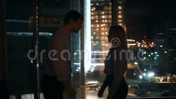 一对年轻夫妇的关系很困难在一扇俯瞰夜城的大窗户的背景下视频的预览图
