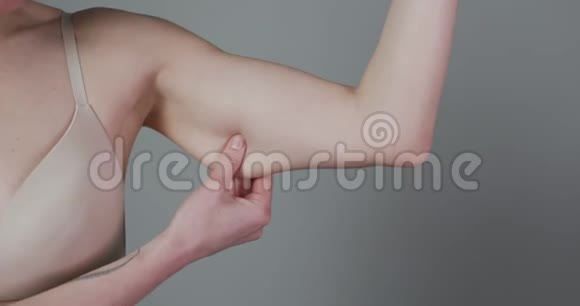 减肥概念胖乎乎的女人捏上手臂脂肪隔离在灰色背景上接近白人女性手视频的预览图