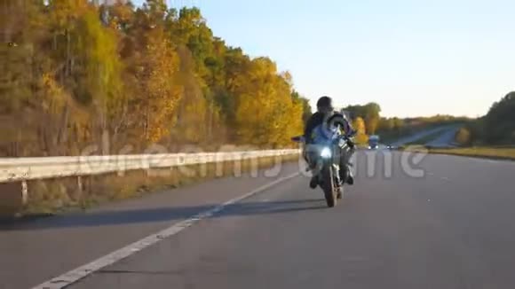 在秋高气爽的高速公路上骑着现代摩托车的年轻人摩托车手在乡间公路上骑摩托车视频的预览图