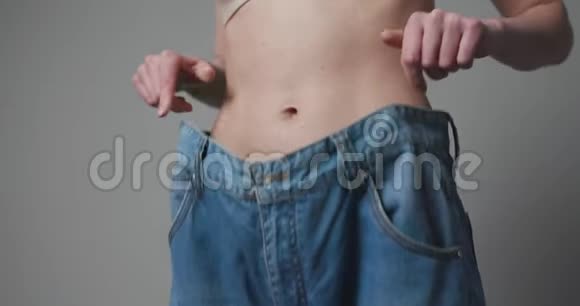 减肥概念年轻的女人展示了她的体重减轻和穿着她的旧牛仔裤穿着大牛仔裤的苗条女孩视频的预览图