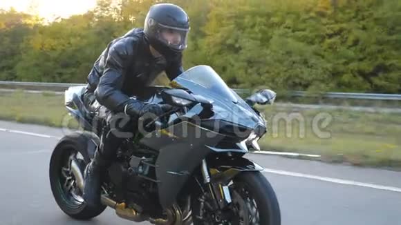 在高速公路上骑着现代摩托车的戴着头盔的年轻人骑摩托车的摩托车视频的预览图