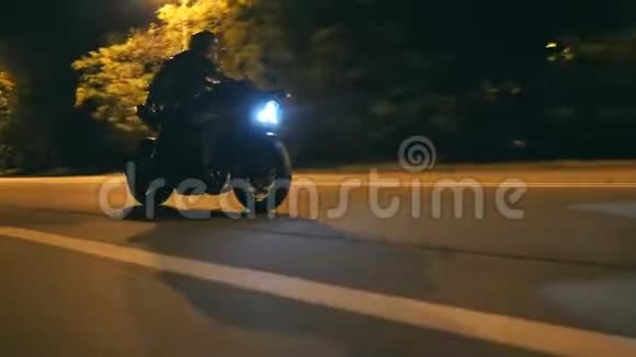 戴头盔的年轻人骑着现代黑色摩托车在傍晚的城市街道他的摩托车手视频的预览图
