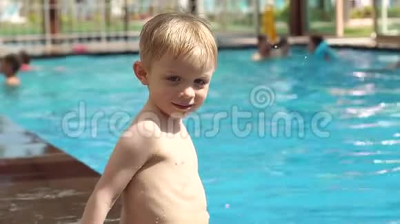 一个小男孩在度假时旅馆的游泳池里的肖像视频的预览图