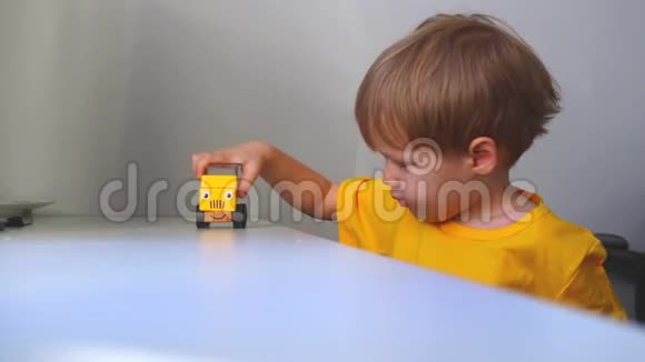 一个男孩在白色的桌子上滚动一辆黄色的车上面画着一张脸视频的预览图