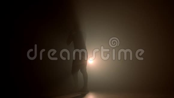 拳击手拳打脚踢的剪影在黑暗烟雾弥漫的工作室里训练视频的预览图