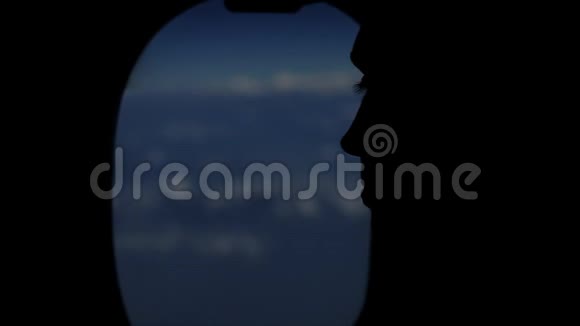 一个剪影的人看着窗外的天空云彩近景面部特征视频的预览图