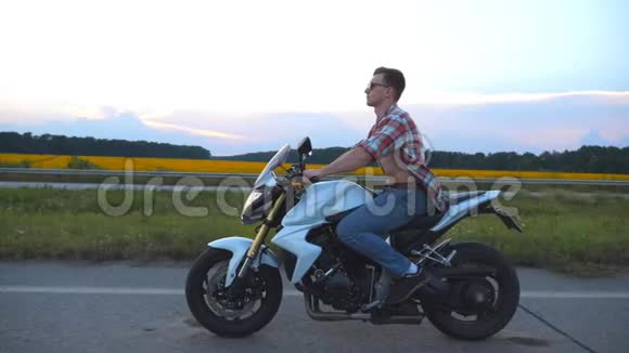 骑着现代摩托车的年轻人穿着衬衫戴眼镜驾驶摩托车的帅气摩托车视频的预览图