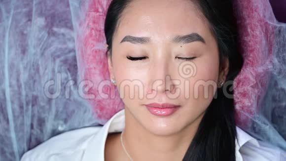 一个美丽的亚洲女人在睫毛延伸过程中睁开眼睛的肖像前后双眼睫毛体积视频的预览图