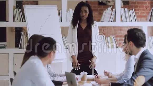 严肃的非洲女经理在会上与员工小组交谈视频的预览图