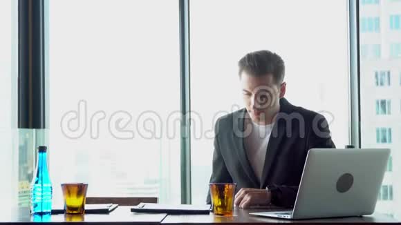 年轻商人在办公室工作触摸智能手机屏幕和笔记本电脑视频的预览图