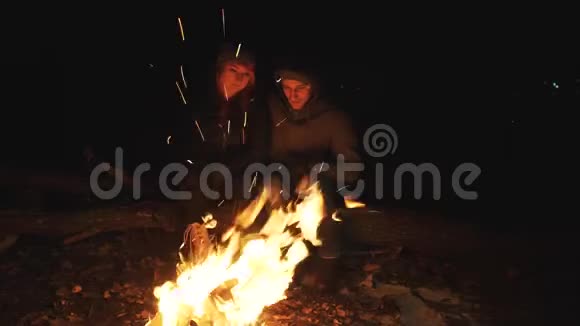在寒冷的秋天一男一女坐在火炉旁拥抱视频的预览图