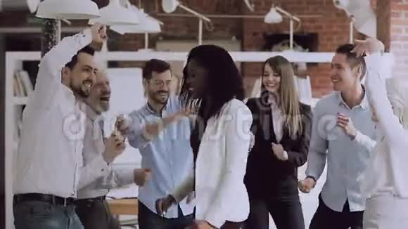 快乐的多元化团队与黑人女领导在办公室跳舞视频的预览图