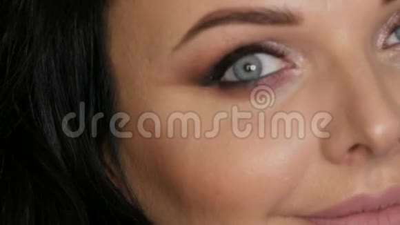 一张美丽的年轻女子的脸部特写照片她用明亮的晚妆和蓝色的眼睛烟熏的眼睛视频的预览图