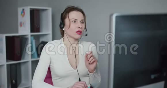 美丽的女性呼叫中心戴头套在网上咨询客户时使用电脑视频的预览图