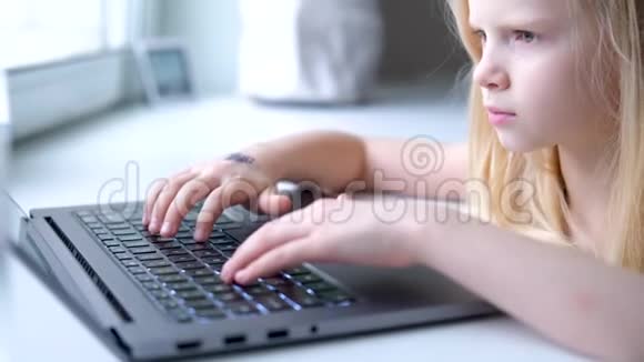 金发小女孩在笔记本电脑上工作学习或玩耍按手指按按钮数字教育视频的预览图
