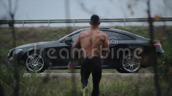 一个肌肉发达的人站在汽车前面汽车与人之间对抗和竞争的概念视频的预览图
