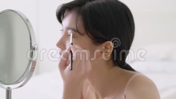 美丽的年轻亚洲女人化妆眉毛刷美丽的亚洲女孩用化妆品化妆风格的镜子视频的预览图