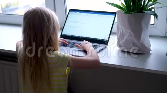 金发小女孩在笔记本电脑上工作学习或玩耍按手指按按钮数字教育视频的预览图