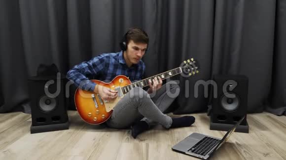 学弹吉他的人戴耳机的年轻男性使用笔记本用电吉他演奏坐在地板上的青少年视频的预览图