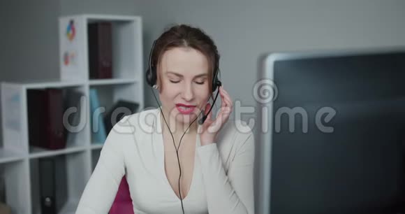 年轻漂亮的女性呼叫中心戴着耳机在咨询在线问题客户时使用电脑视频的预览图