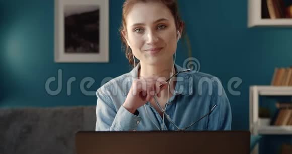 带着笔记本电脑坐在办公桌前微笑的女人的肖像视频的预览图