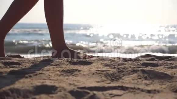 在阳光明媚的日子里雌性的脚在海边散步背景是波浪年轻女子踩在沙滩上的腿视频的预览图