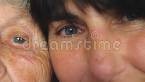 老妇人和她成年女儿一起看镜头的眼睛又老又年轻的脸细节视图视频的预览图