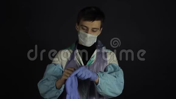 一个年轻的白种人戴着医疗手套看着相机穿着医用防护服孤立存在视频的预览图