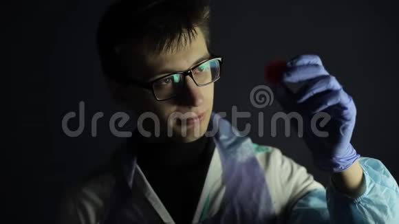 一位戴着防护服装眼镜的科学家在看一个冠状病毒COVID19模型黑暗的背景视频的预览图
