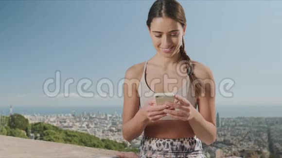 女人坐在莲花姿势与智能手机城市里用手机的女孩视频的预览图