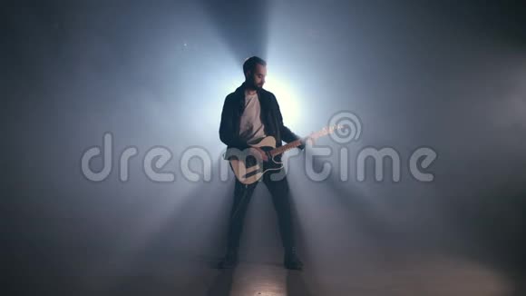 摇滚吉他手男子在烟雾弥漫的舞台和熟练地演奏电吉他视频的预览图