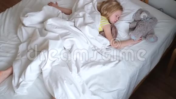 金发的小女孩睡在大床上床上铺着白色的床上用品上景孩子们做梦童年平静夜晚4K录像视频的预览图