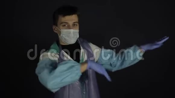 穿着医疗服和面具跳舞的疯狂医生孤立的黑色黑暗的背景很开心视频的预览图