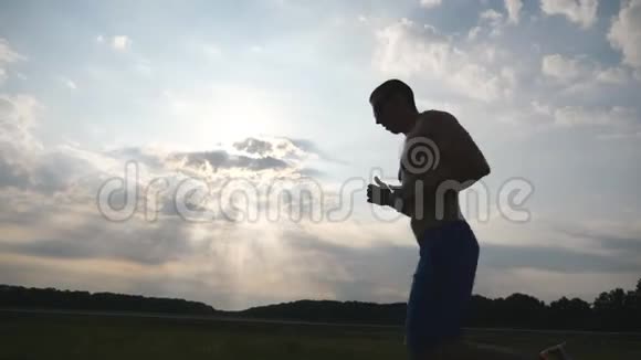 日落时分在乡间小路上慢跑的肌肉男剪影马拉松跑男性慢跑训练概况视频的预览图