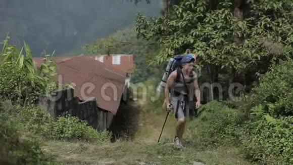 一个白人游客带着背包步行沿着狭窄的尼泊尔石街徒步旅行尼泊尔村庄视频的预览图