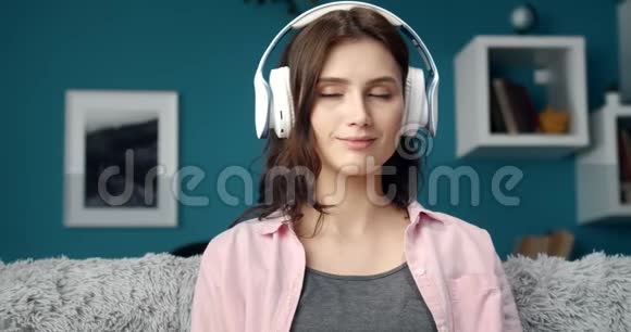戴着耳机的女孩坐在沙发上听音乐视频的预览图